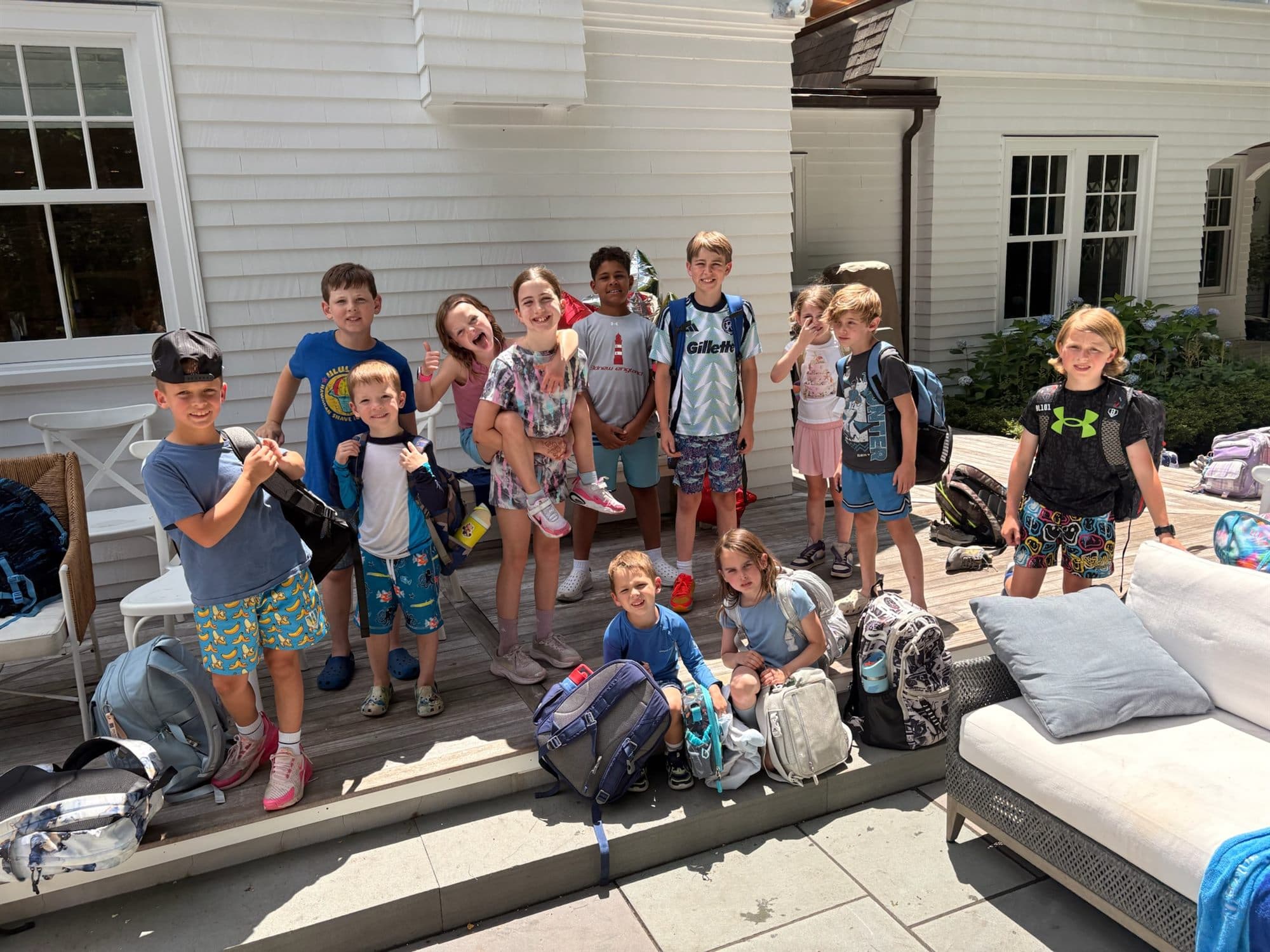 Campers gathered on the patio with their backpacks and gear at the end of a camp day.